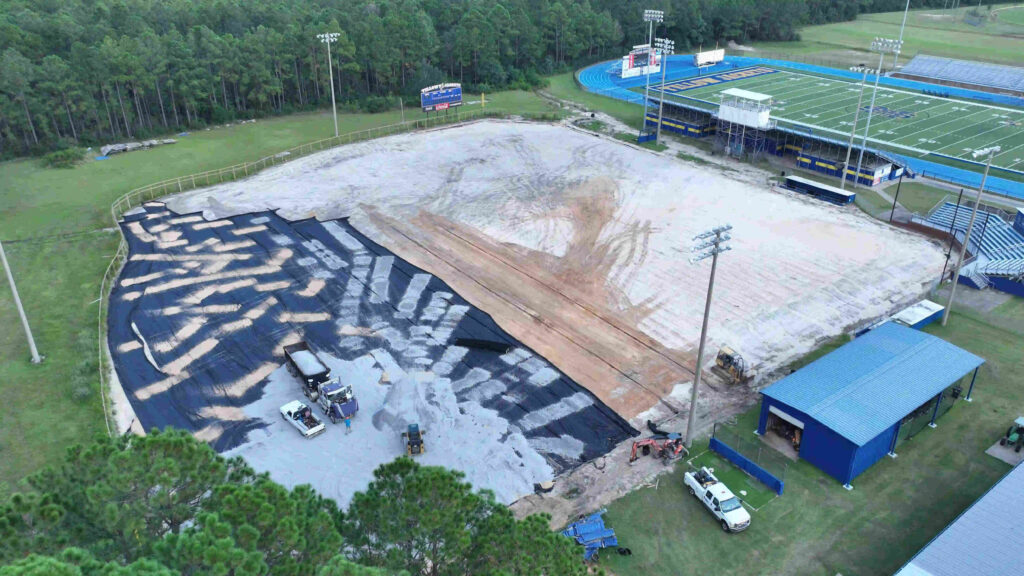 Certified track builders preparing the base of a sports track during the first construction stage.