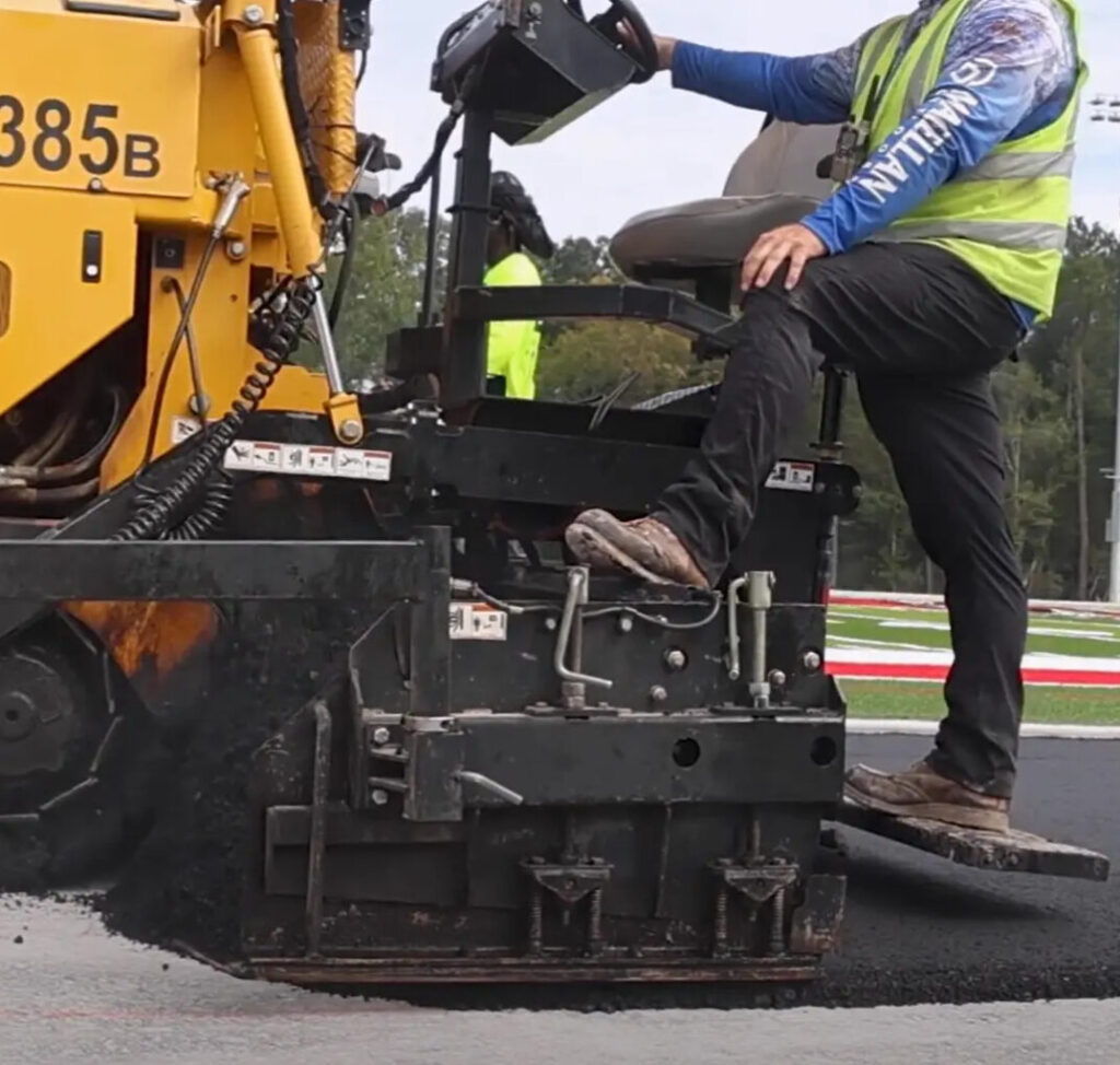 Professional track builders installing the synthetic track surface during the final construction stage.