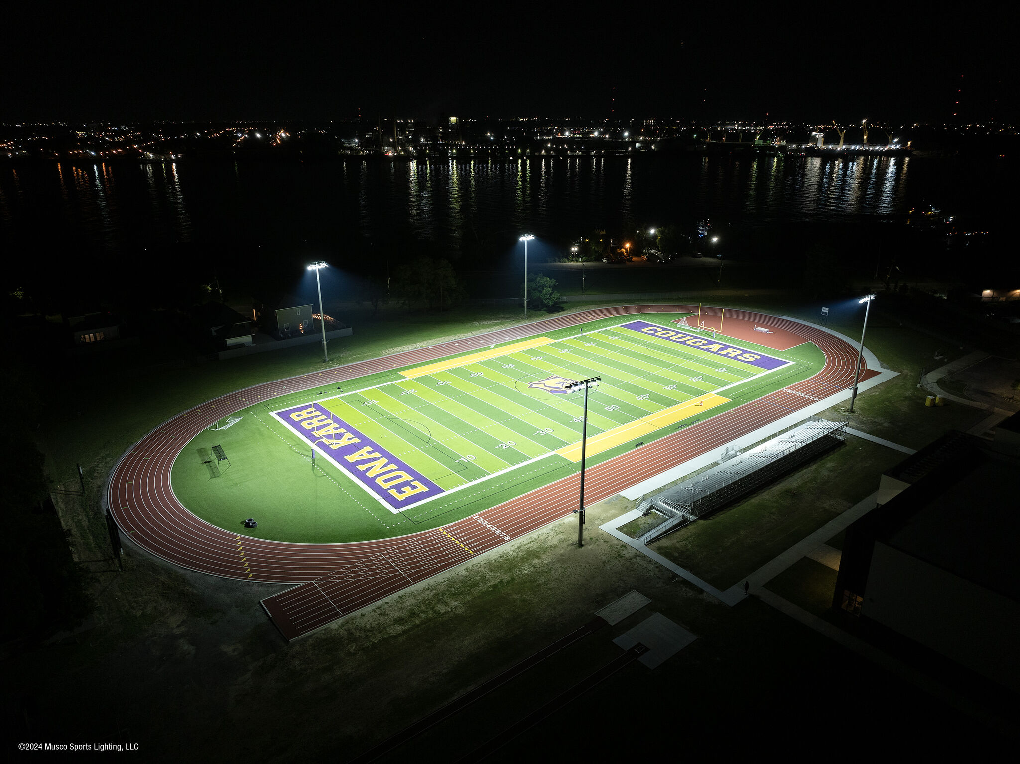 Energy-efficient Musco sports lighting illuminating an outdoor turf field installation at night.